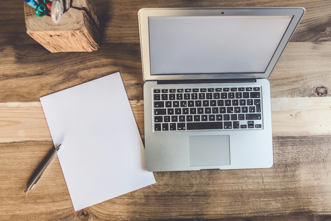 open laptop beside a printed checklist on a wooden desk