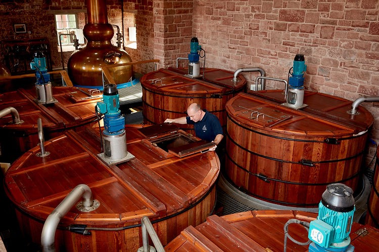 A man working over wodden casks in a whiskey distillery