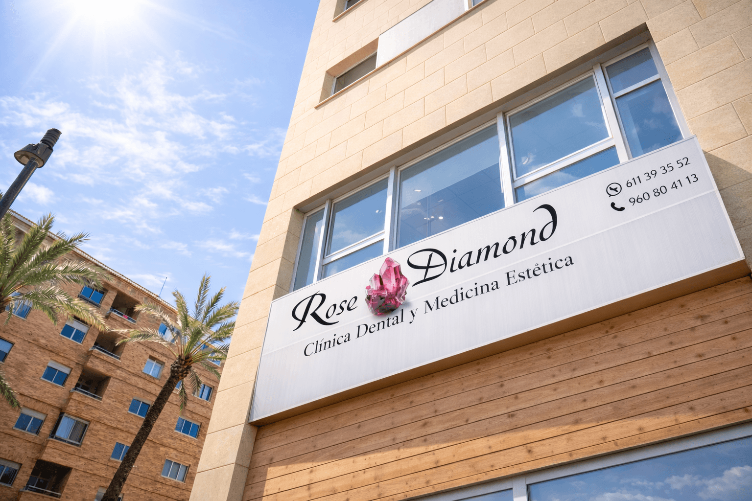 Modern glass office building with white framing, lawn, trees, and clear sky