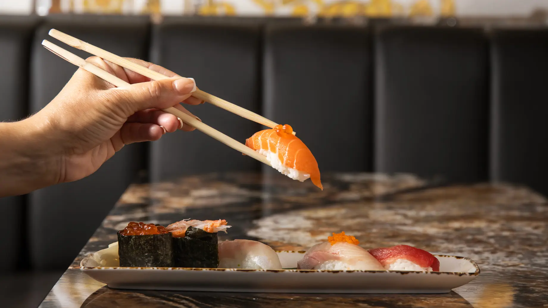 Hand holding salmon sushi with chopsticks