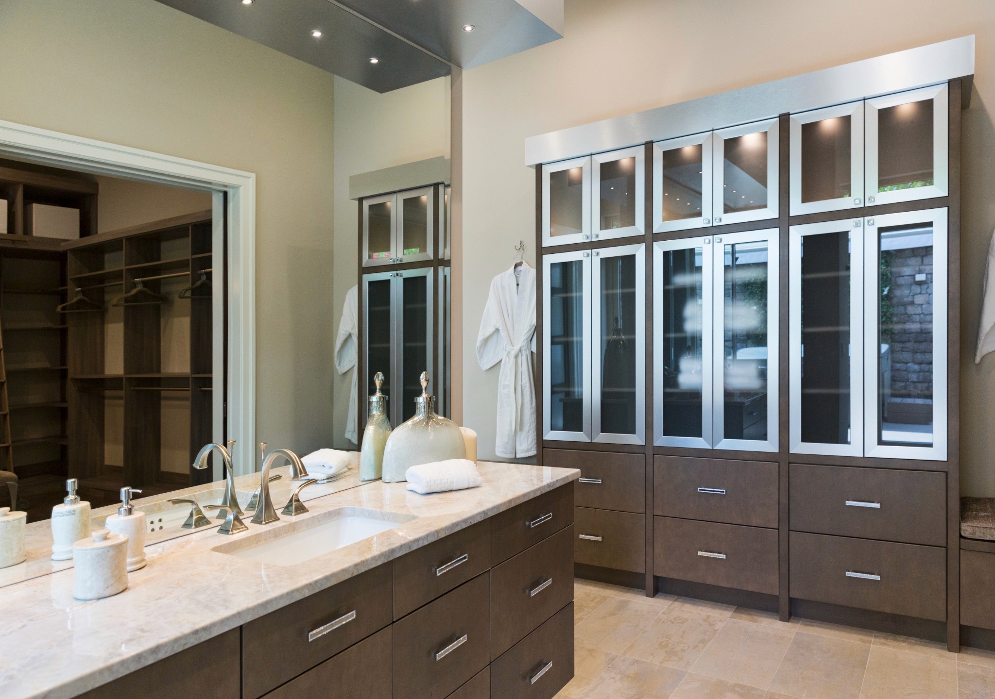 Luxurious bathroom renovation featuring floating vanity with under-cabinet lighting, sleek bronze-toned cabinetry, dual sinks, and frosted glass storage units, reflecting B&Y Reno Corp’s attention to detail and modern design in home remodels.