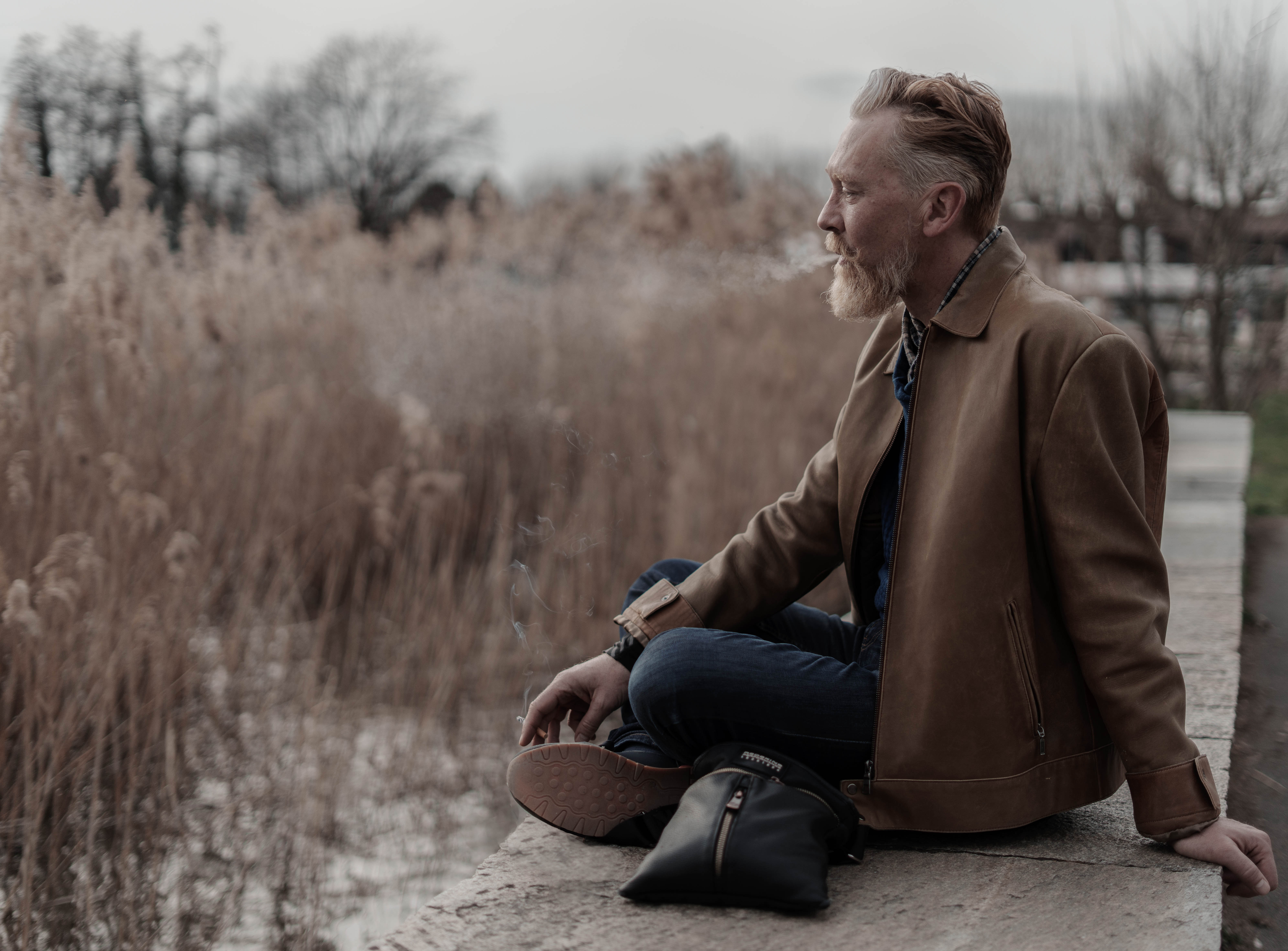 portrait homme fume cigarette assis dans nature