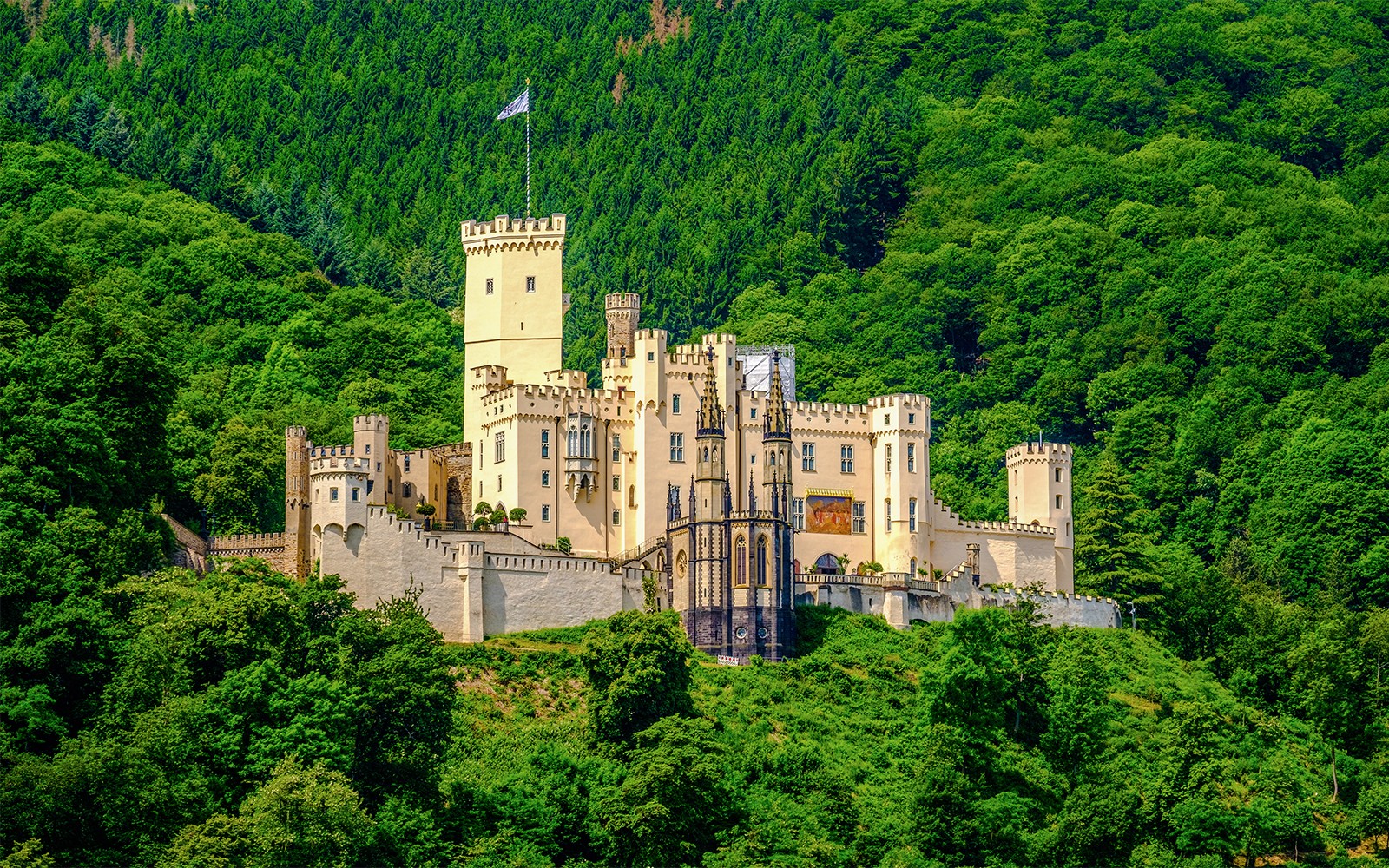 Stolzenfels Castle surrounded by lush greenery, viewed from Koblenz sightseeing cruise.