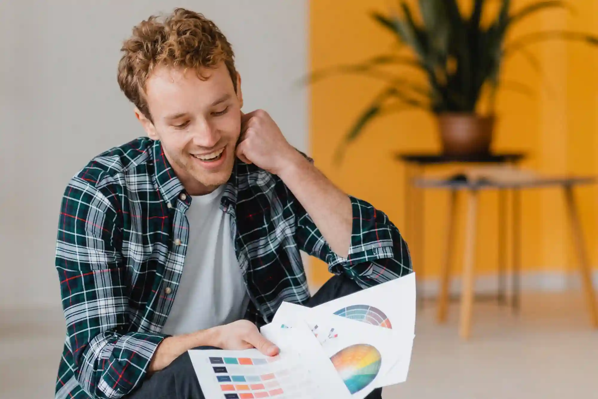 Smiling man reviewing color palettes and design options for a project, demonstrating focus and creativity.