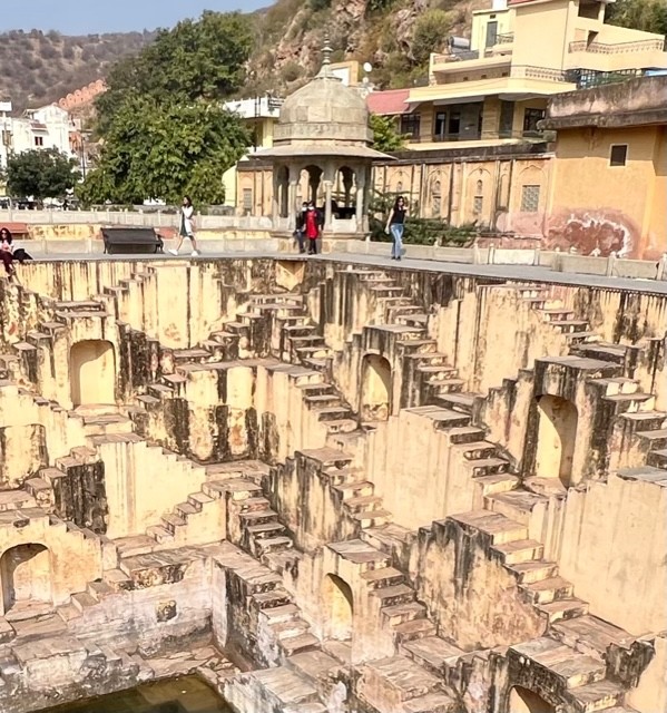 Yellow coloured step well with symmetrical steps criss-crossing along the walls along its 8 levels. An octagonal recess is built at each level