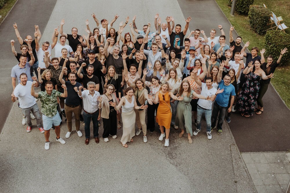 Team photo of the agency, people looking at the camera and waving