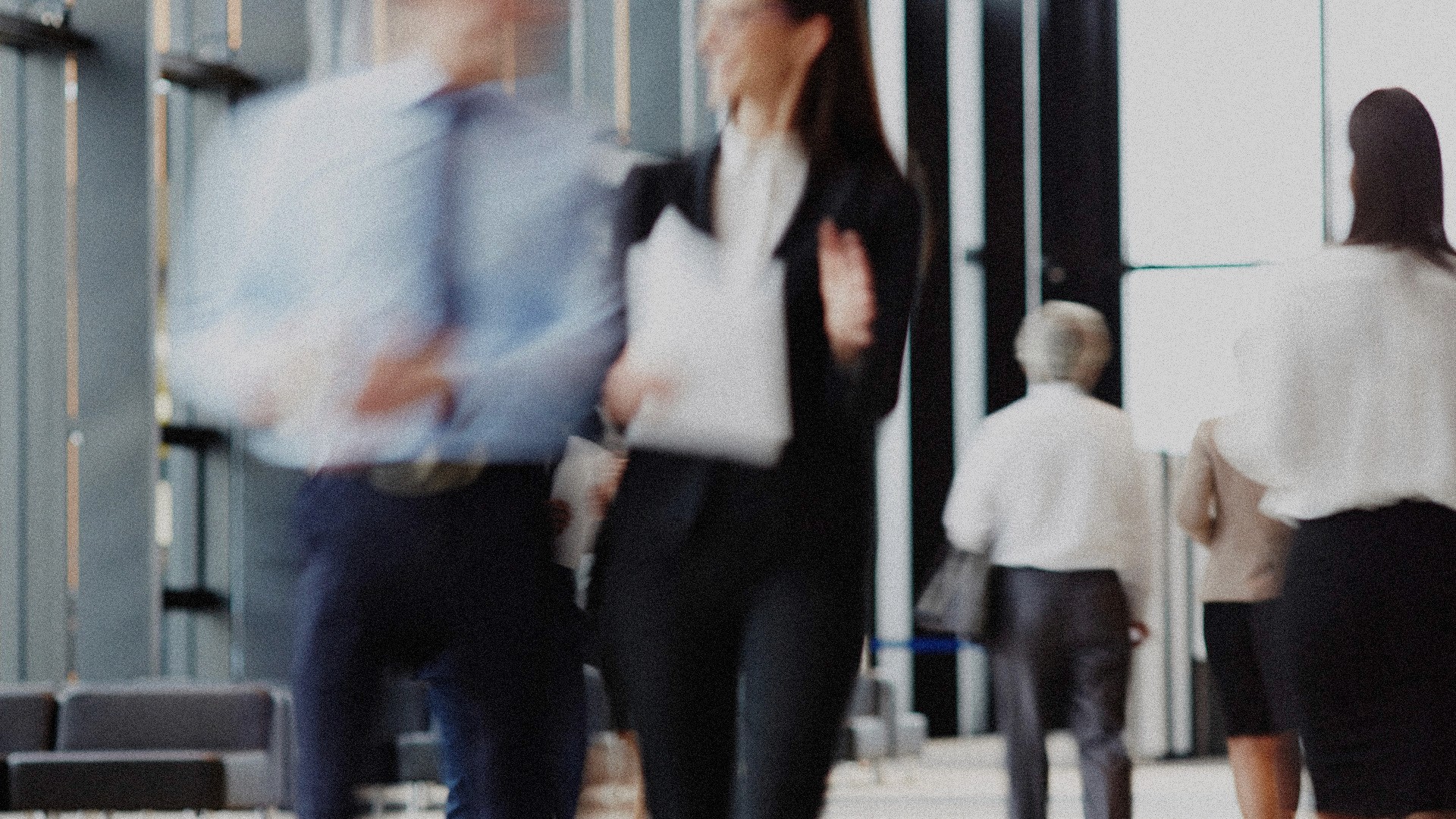 A motion blur and grainy image of people walking outside of an office.