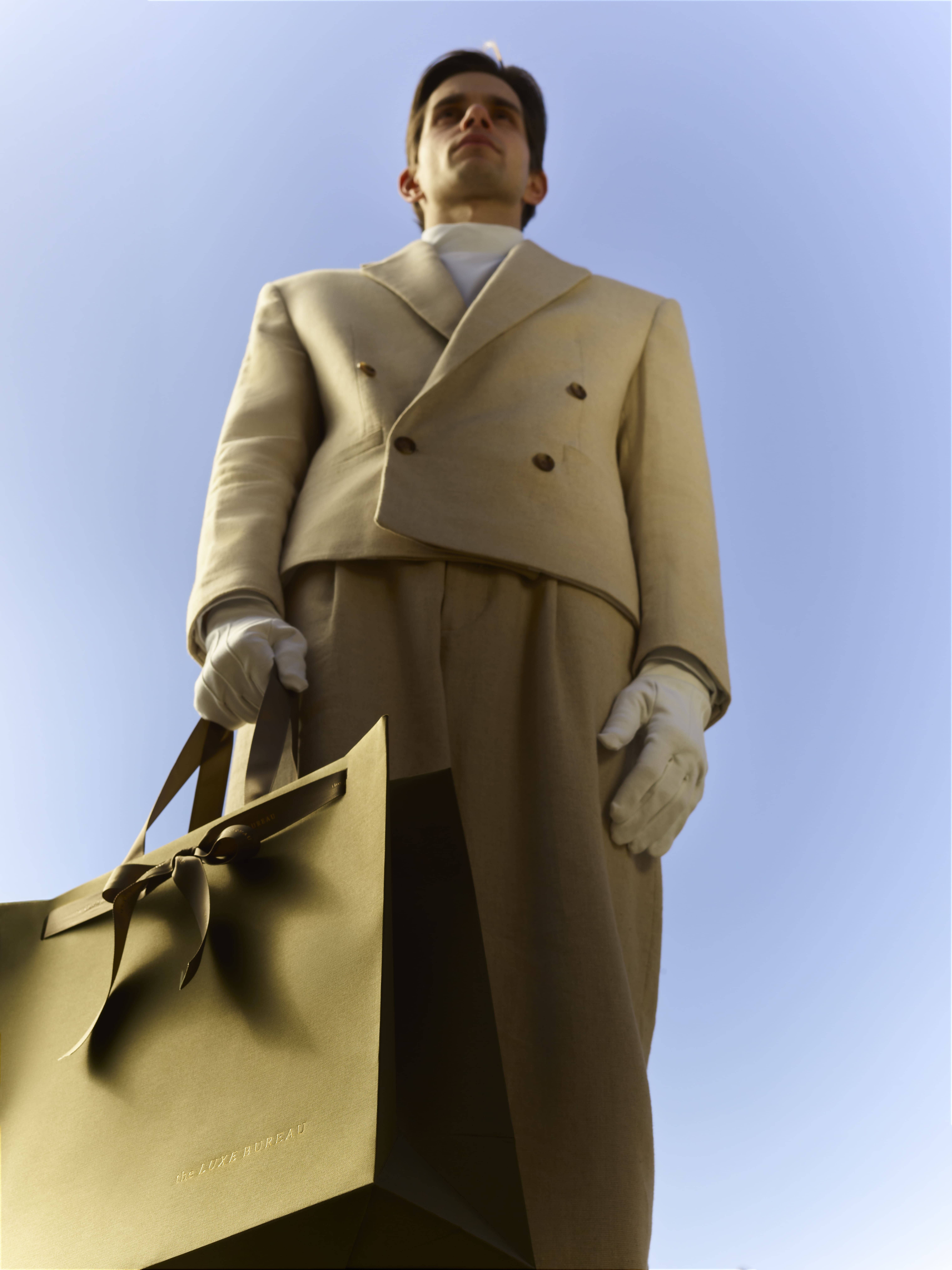 the luxe bureau model standing in front of branded posters and luxury gift bags