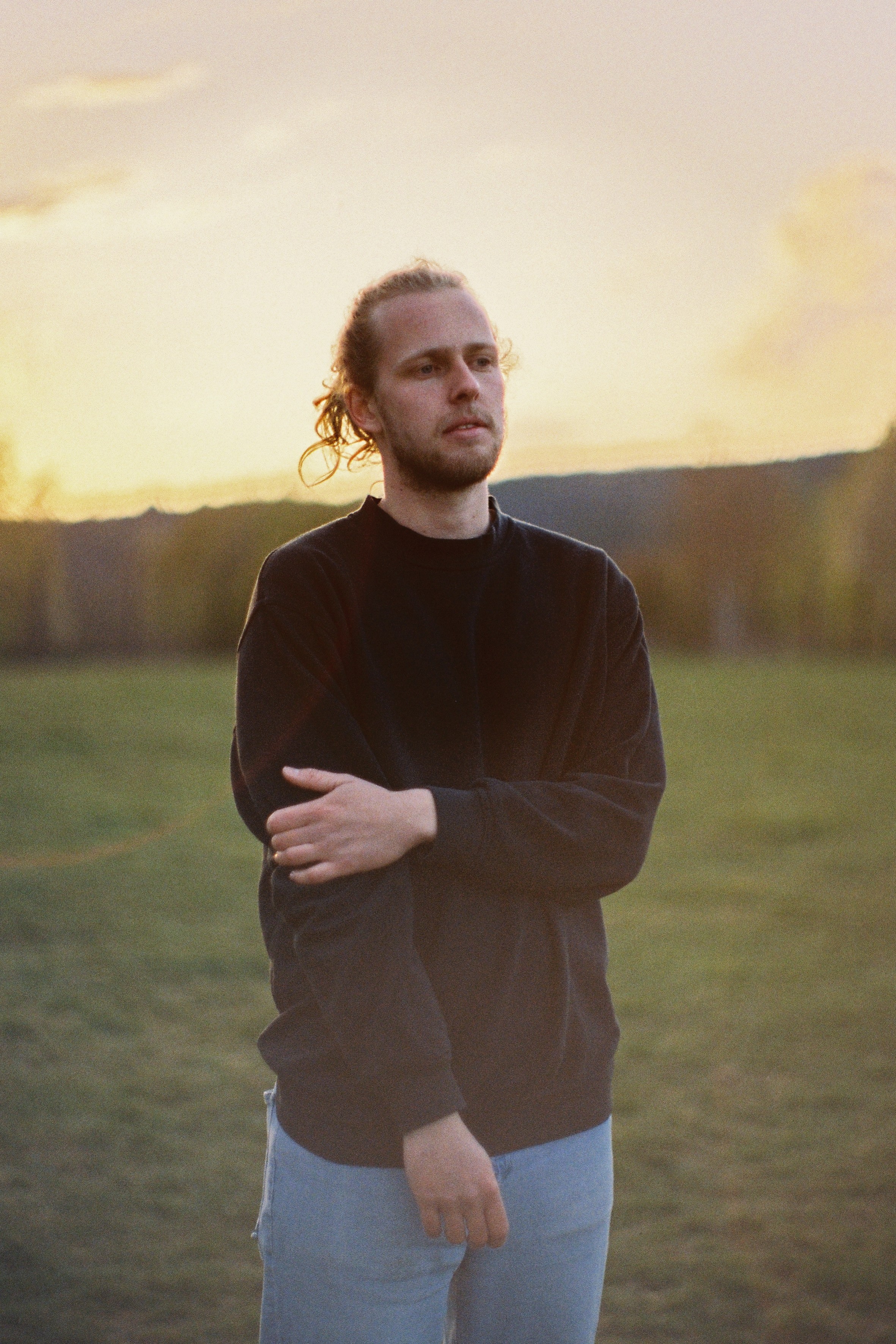 A man with glasses and a brown shirt, crossing his arms.