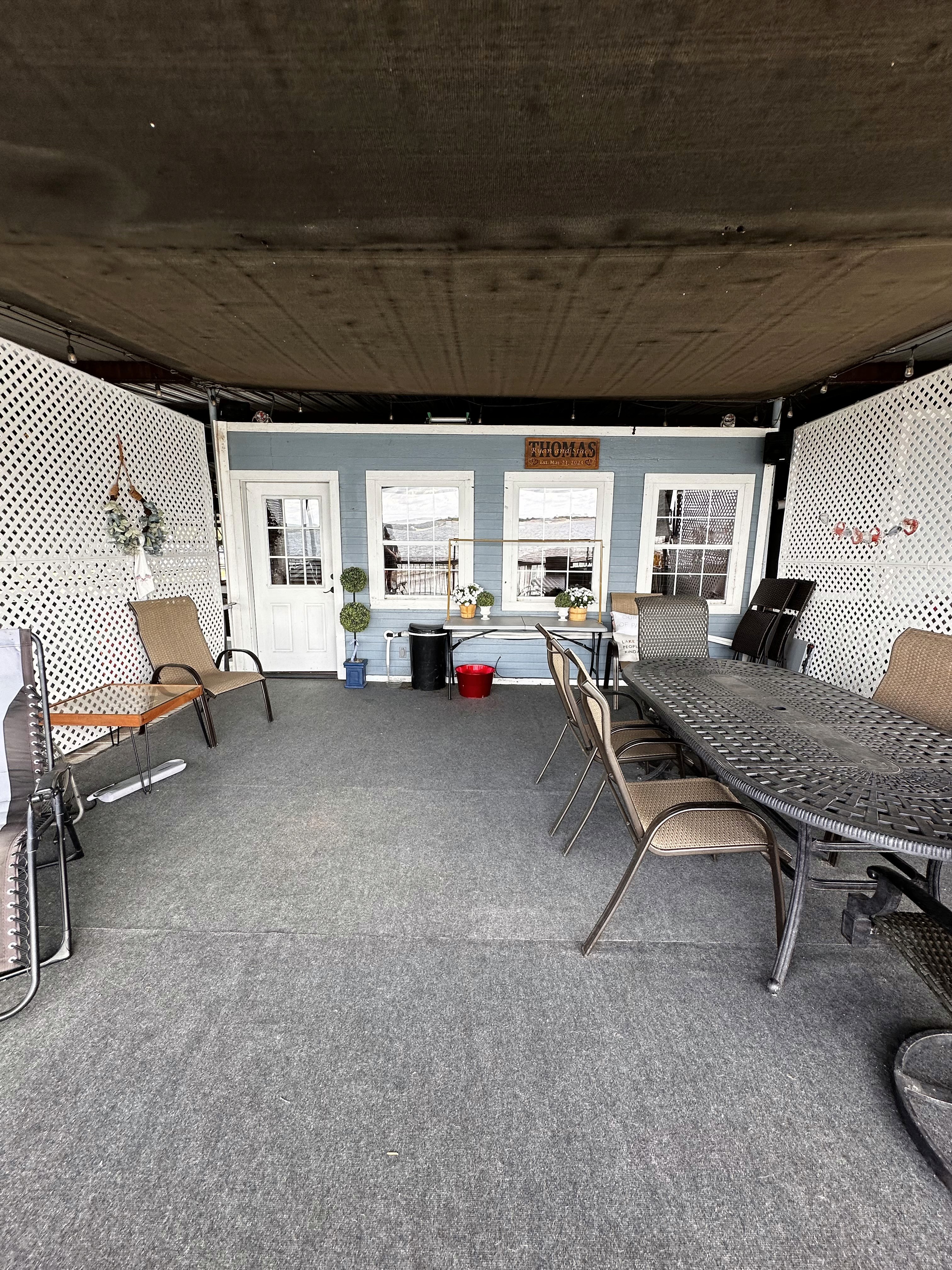 Covered outdoor patio with a seating area, dining table, and various decorative plants.
