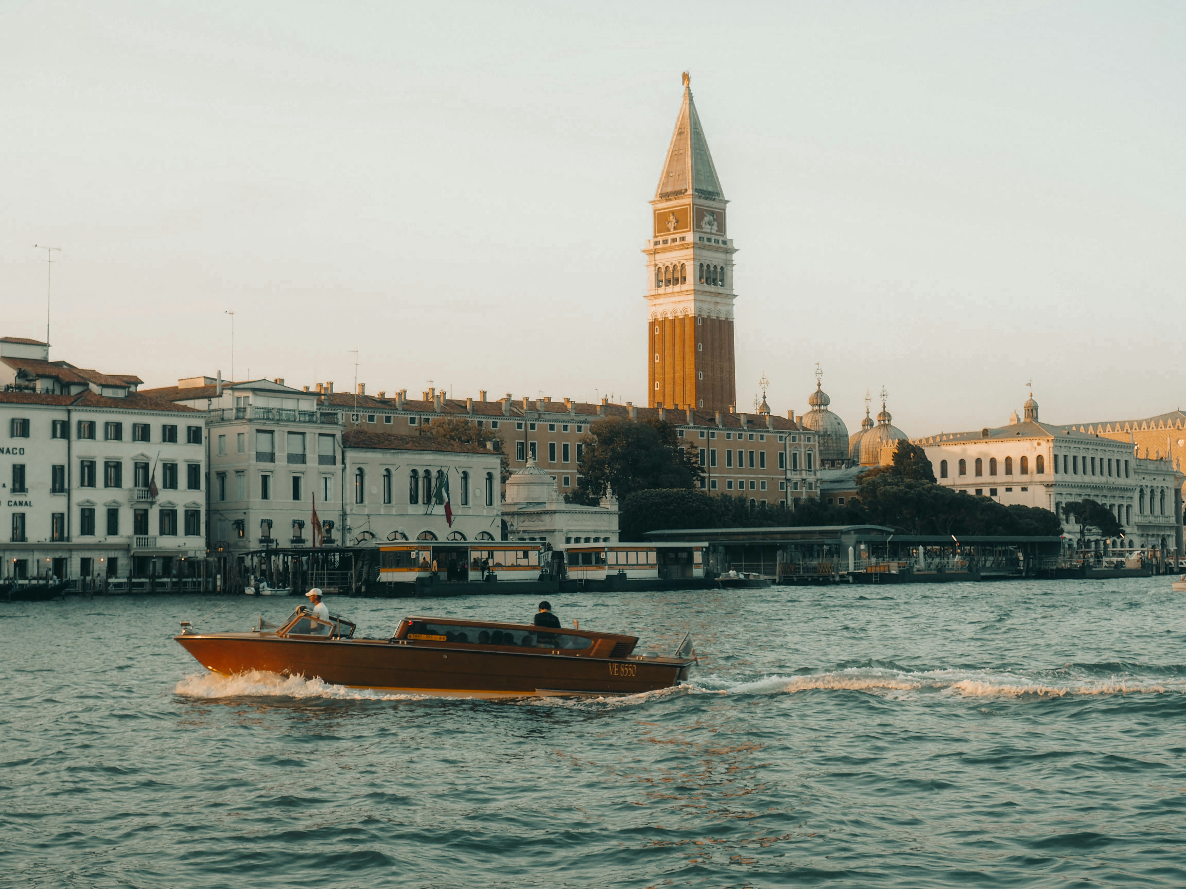 A boat travels on a canal in front of buildings.