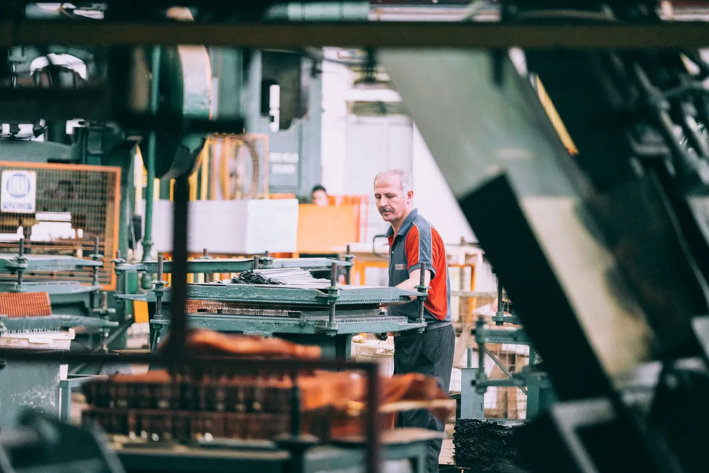 Fachkraft arbeitet an einer Maschine in einer Produktionshalle