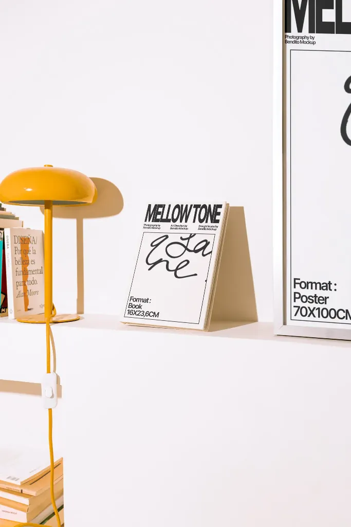 Minimalist display featuring a book in yellow and blue on a white shelf, accompanied by a retro yellow lamp and books. Perfect for modern interior or design themes.
