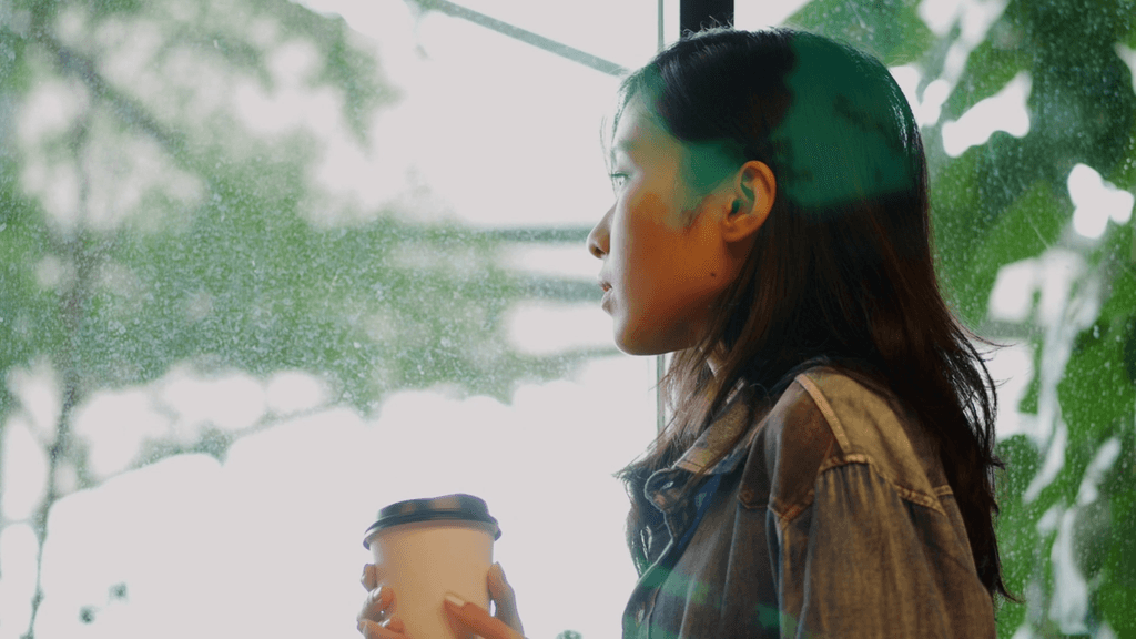 Filipina woman drinking a hot drink while looking outside the window