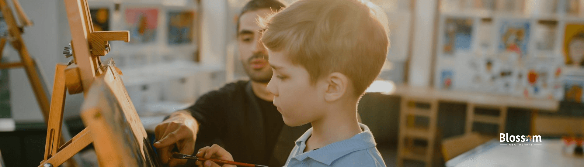 A young boy with autism painting with a BCBA at an art class during ABA therapy in Tennessee.