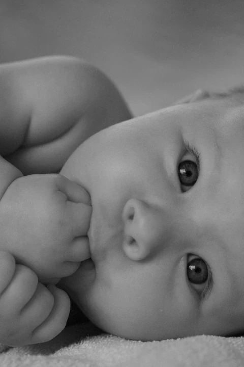 Black and white close-up of a baby holding a blanket