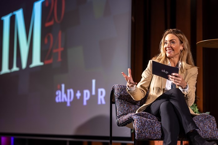 A person wearing a virtual reality headset stands in front of multiple screens, engaged in a digital experience.