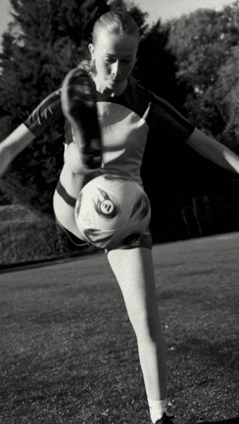 Bride sitting on ground against wall, groom standing nearby