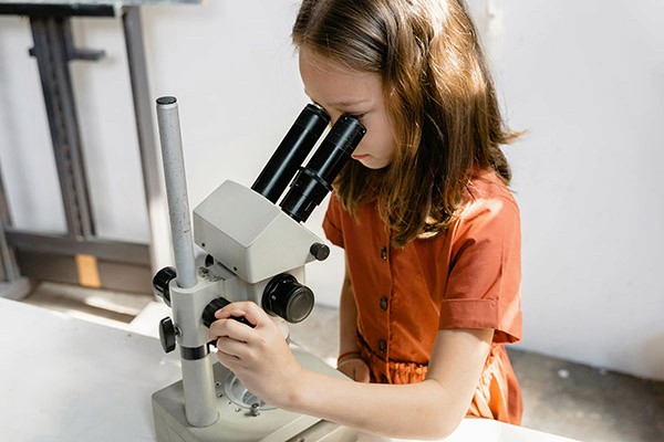 Niña mirando por microscopio
