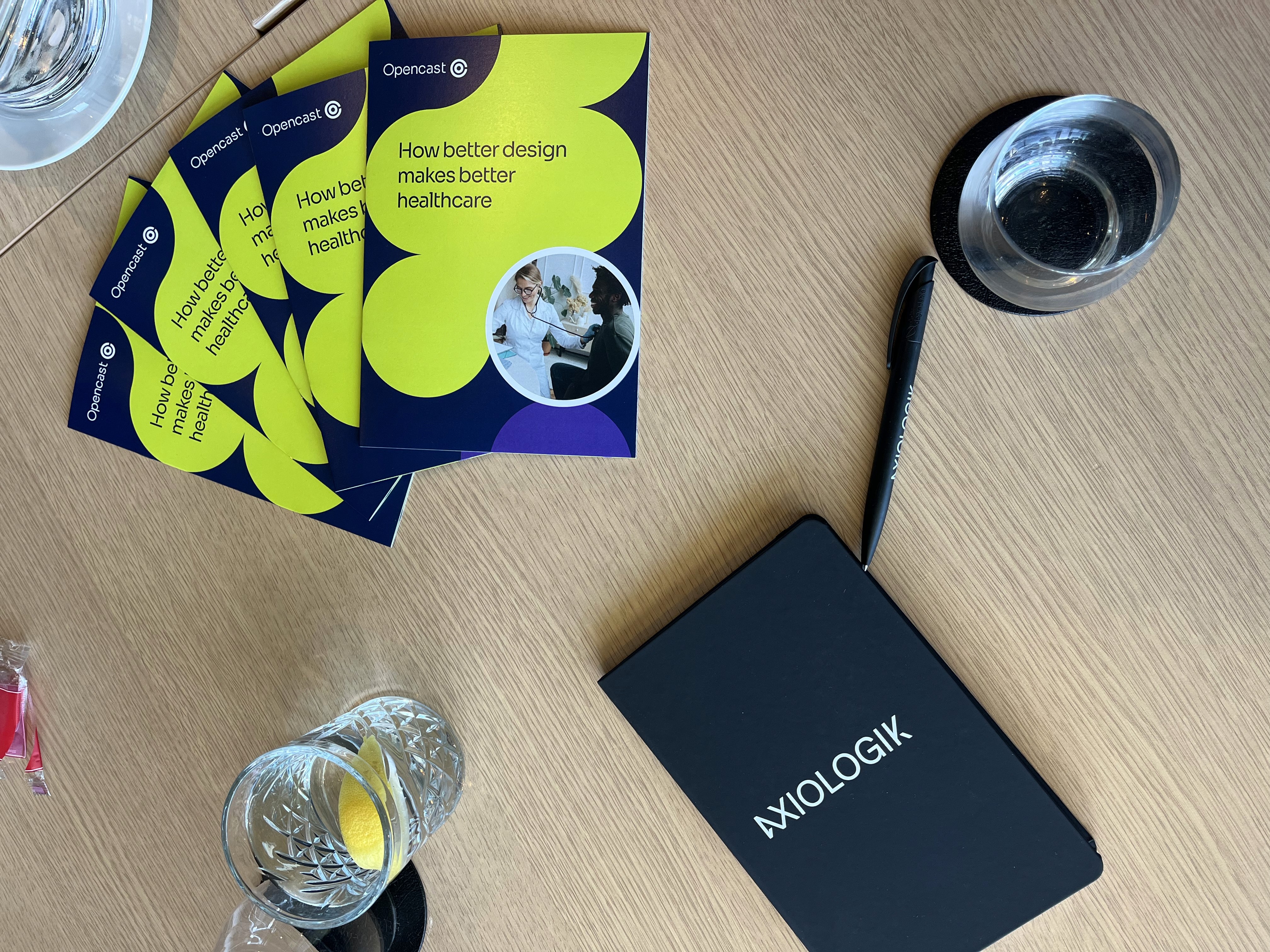 Opencast healthcare leaflets on a table next to a notebook, pen and drinks.