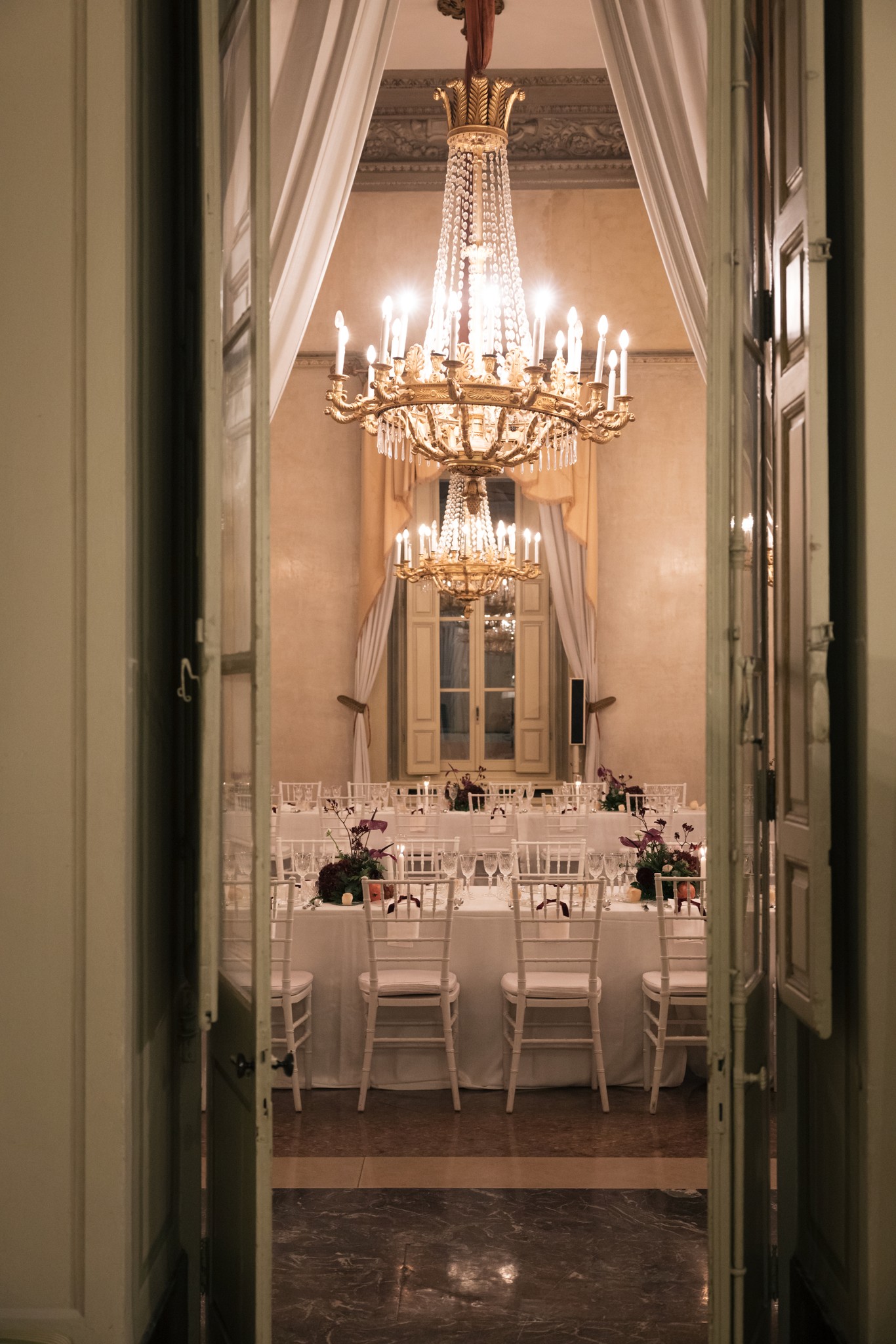 Sala ricevimento con lampadari in cristallo, tavolo allestito per matrimonio al Circolo di Lettura di Parma, luci calde