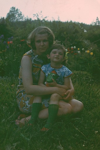 Ema ja laps istuvad aias muru peal