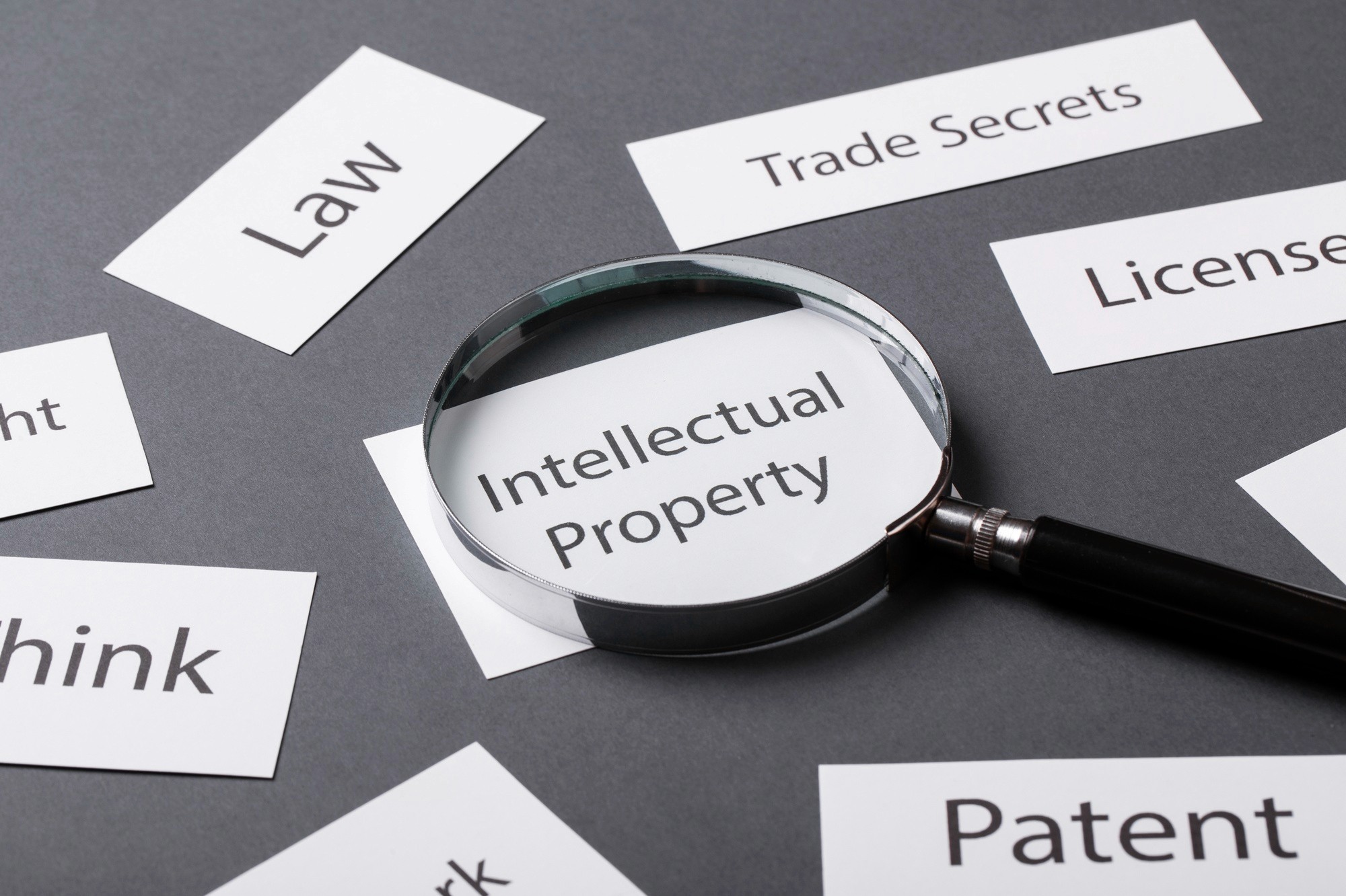 “Intellectual property law concept with magnifying glass highlighting patents, trade secrets, and licensing terms”