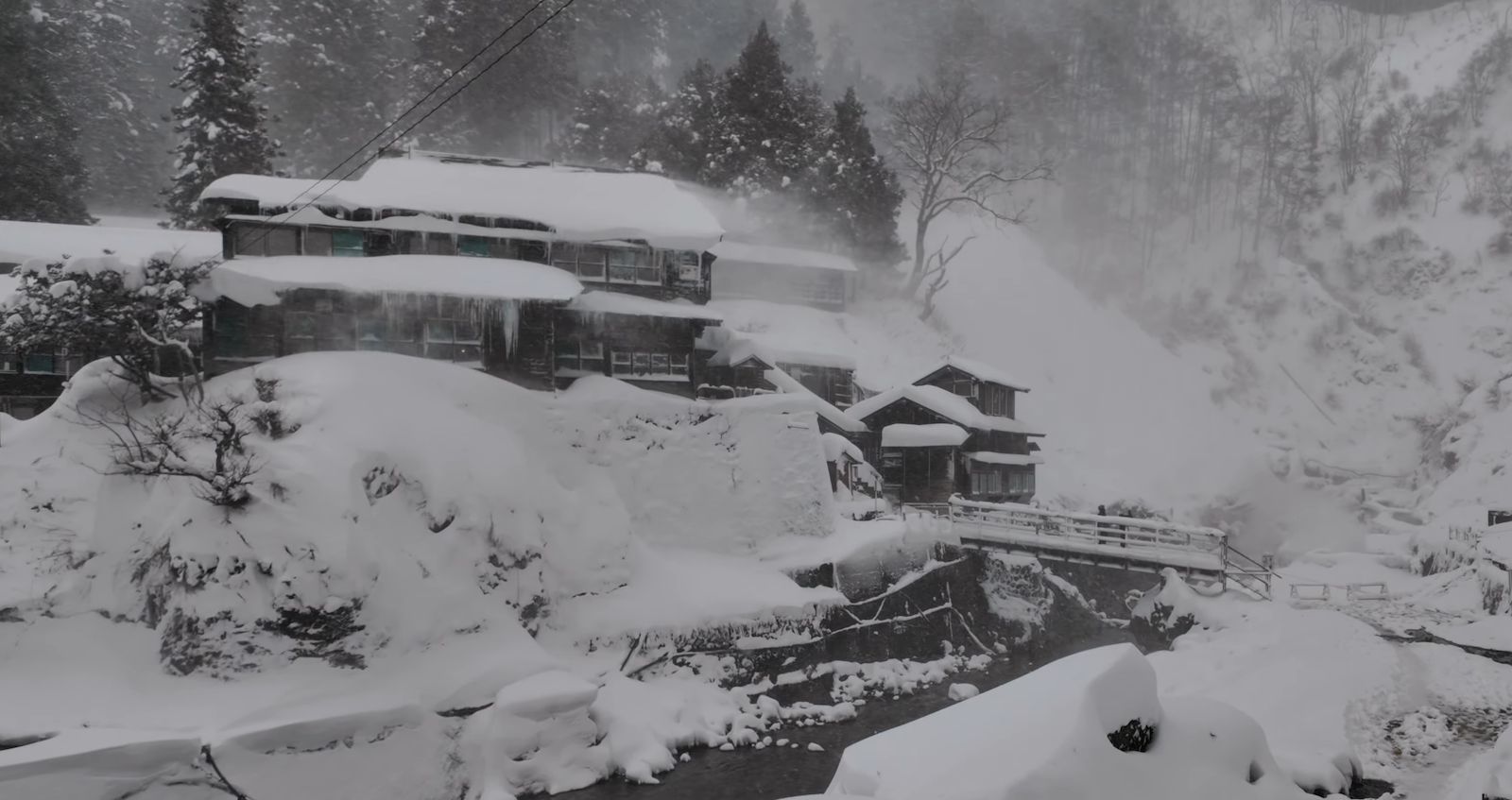 Traditional onsen ryokan buildings under deep winter snow