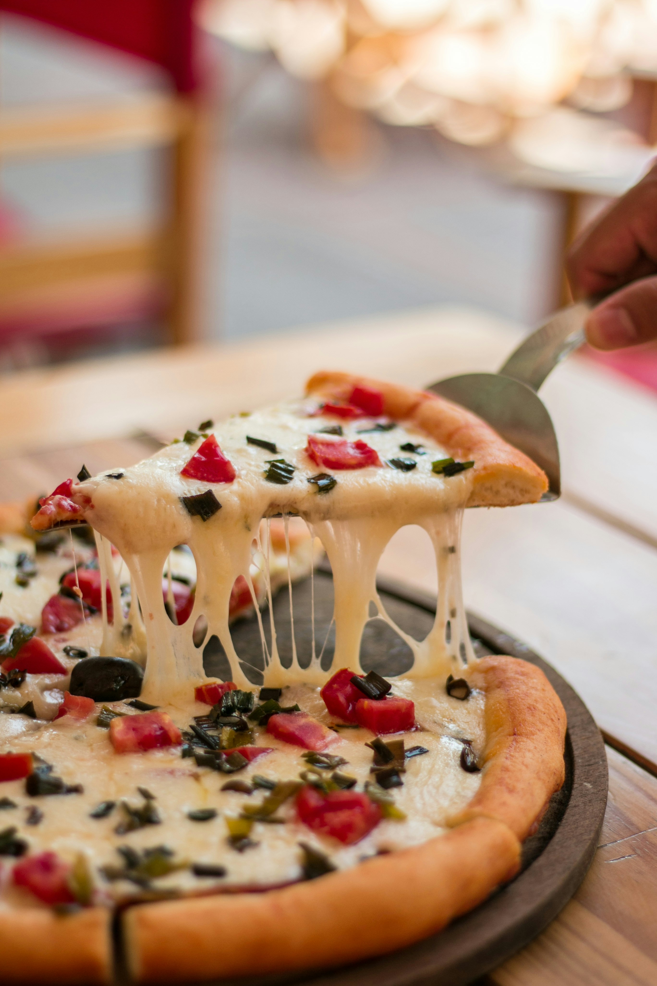 A person cutting a decorated pizza with chocolates.