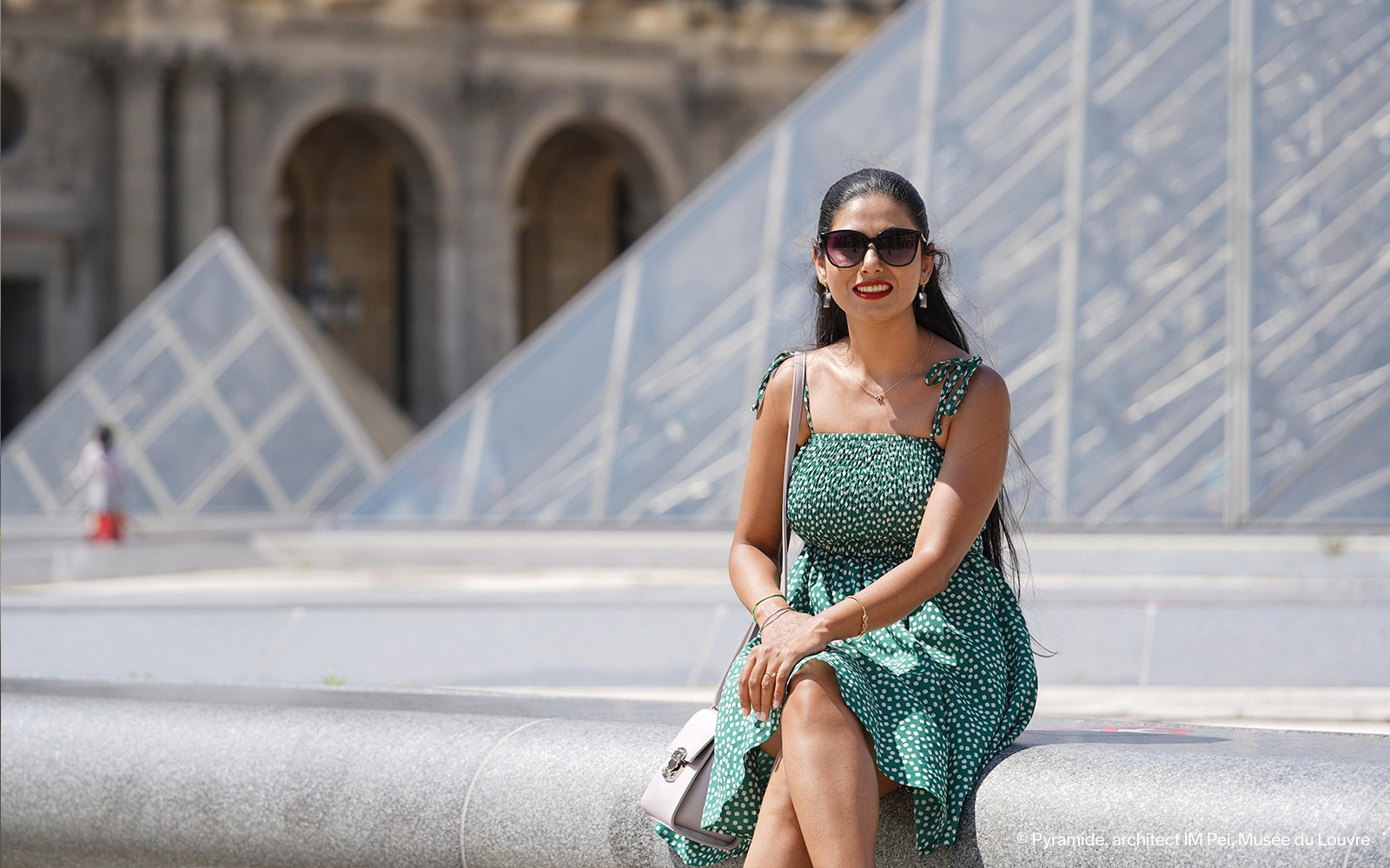 Người phụ nữ ngồi trước Kim tự tháp Louvre trong buổi chụp ảnh chuyên nghiệp ở Paris.