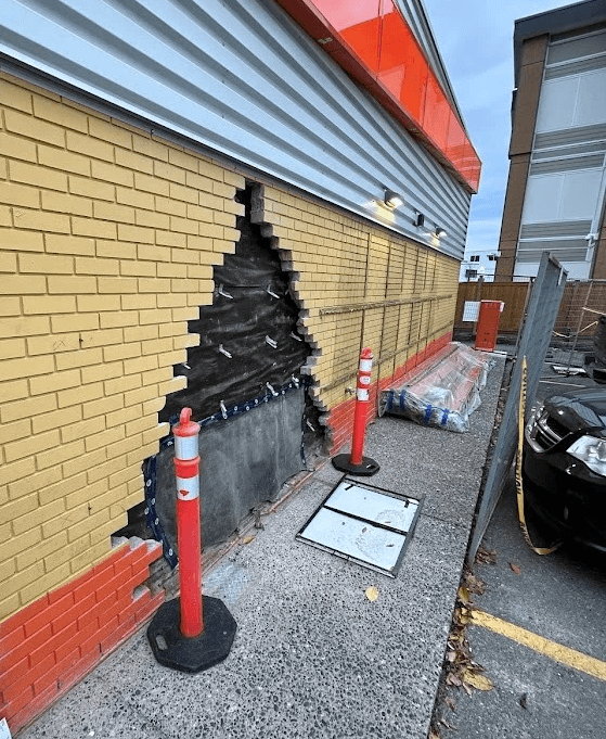 Damaged brick wall with safety cones