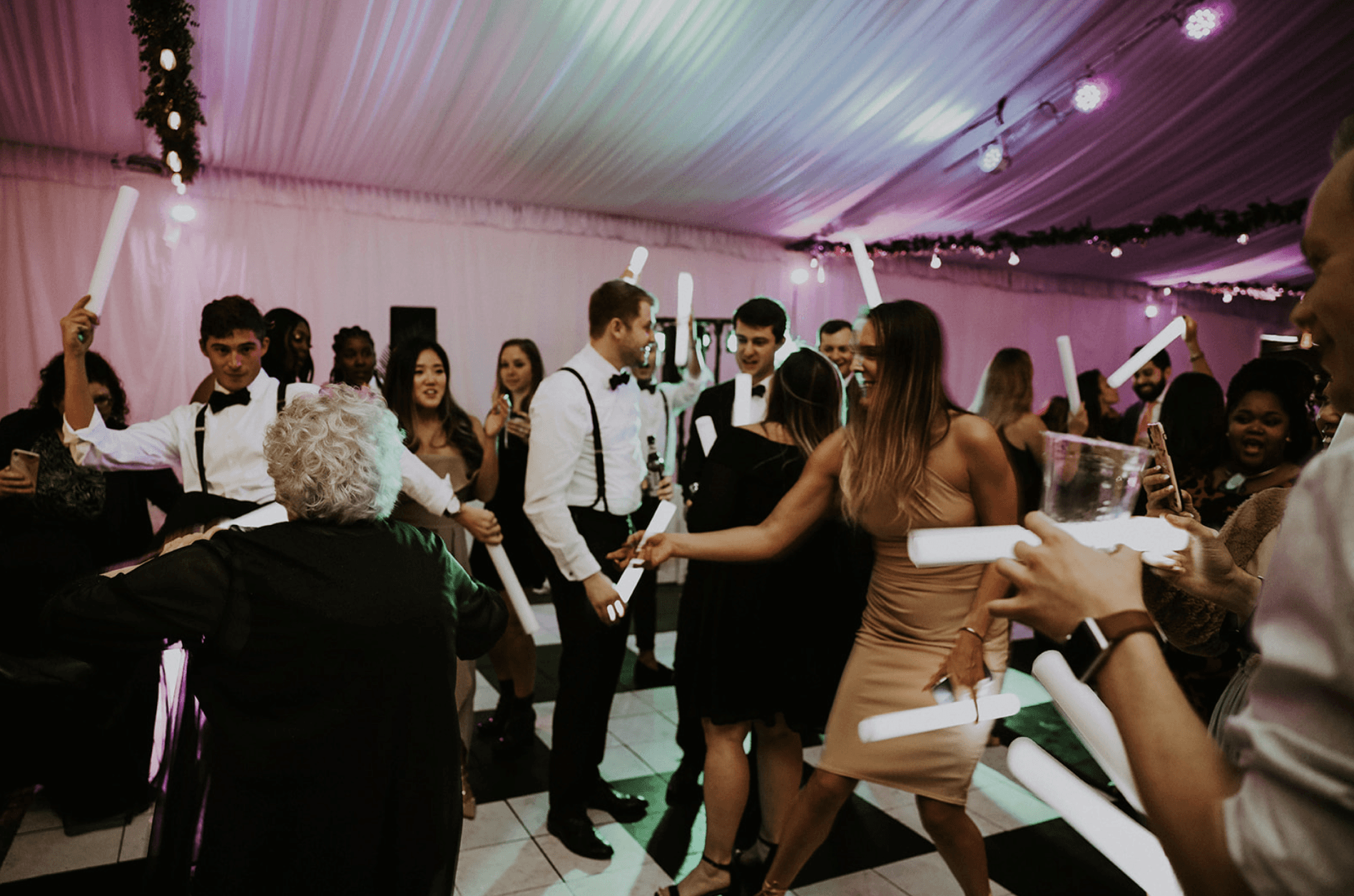 Guests dancing with glowing foam sticks beneath colorful reception lights at Park Tavern Garden Tent.
