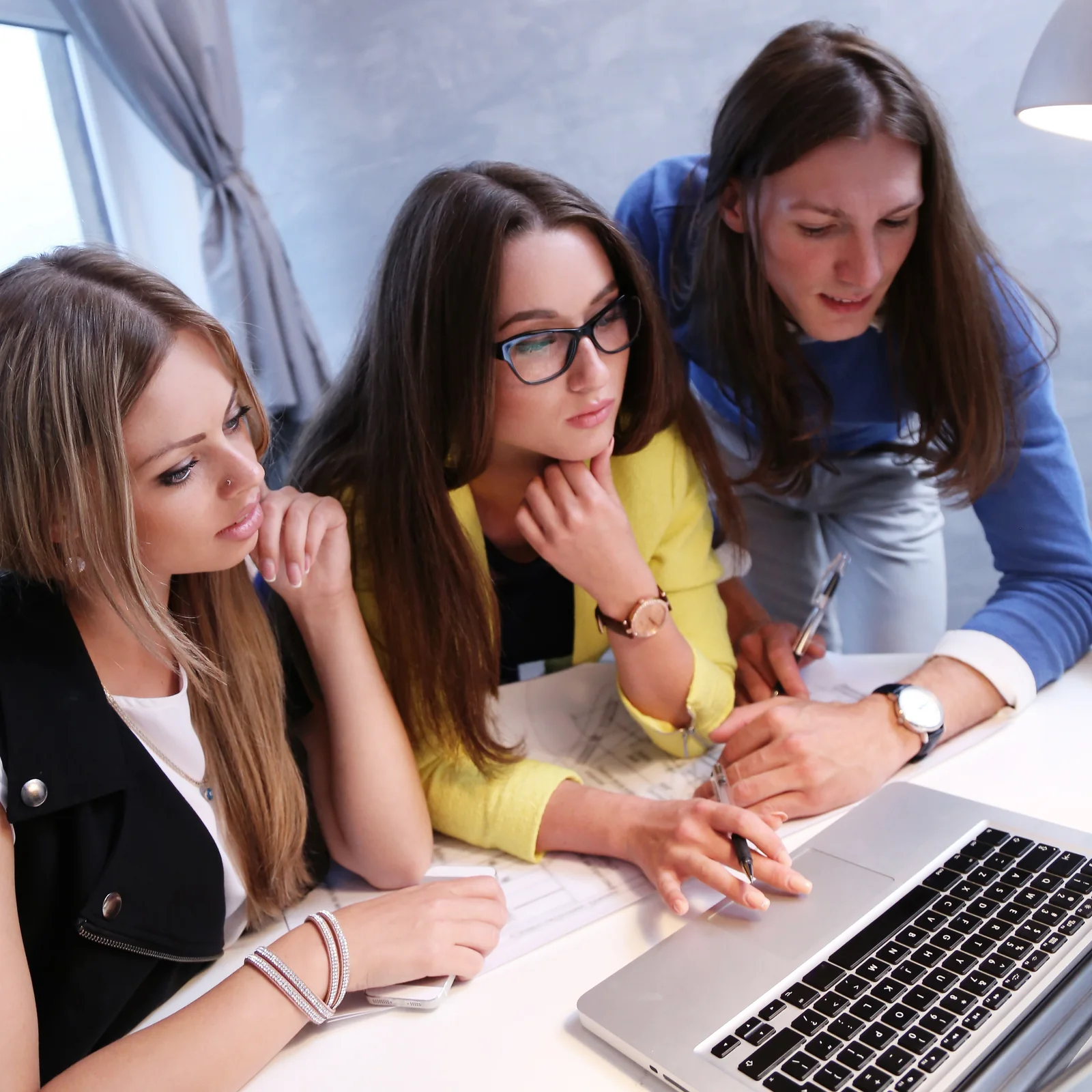 Three Colleagues Collaborating on a Laptop in Workplace