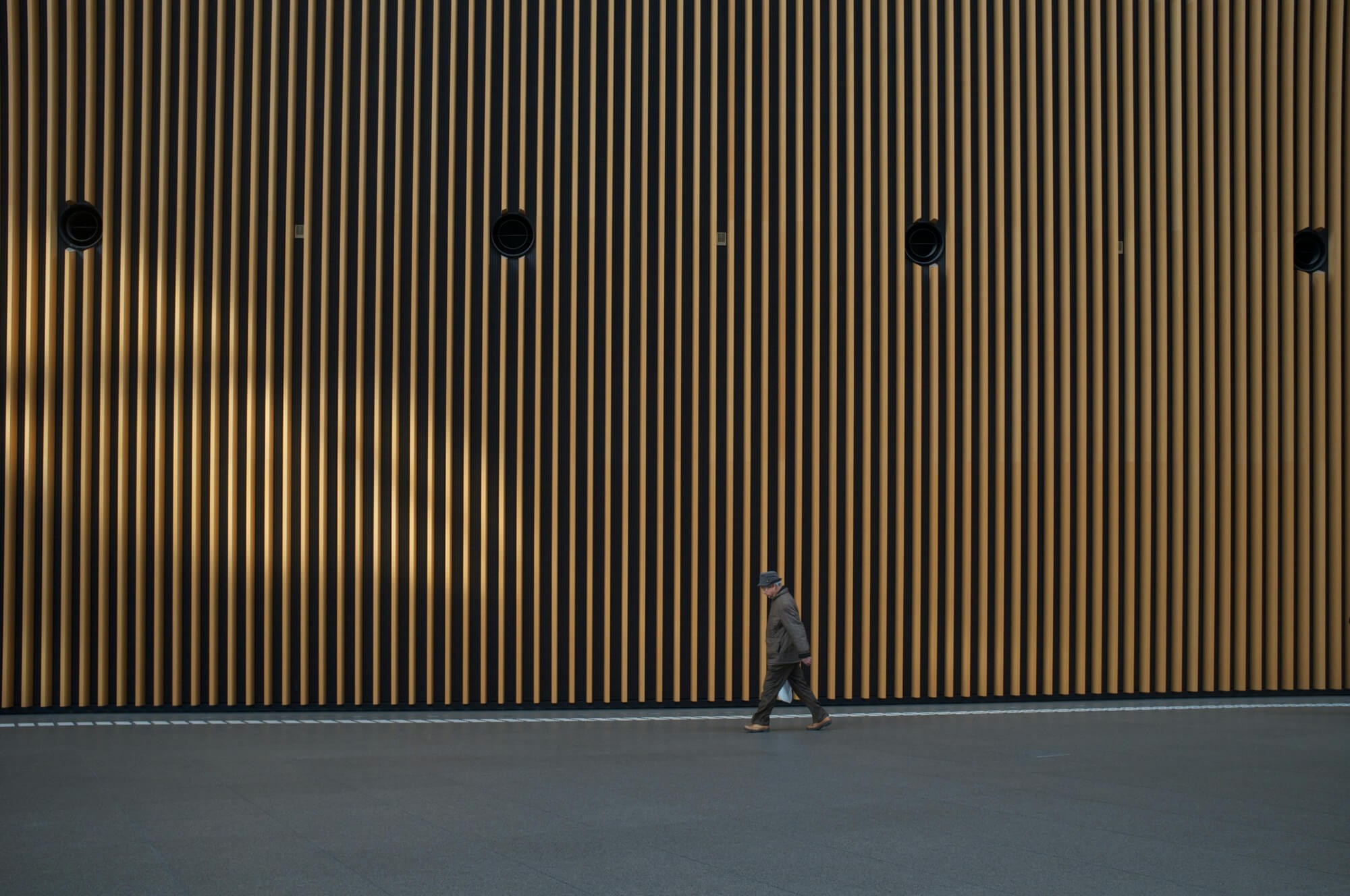 Man walking in front of a big wood plank facade