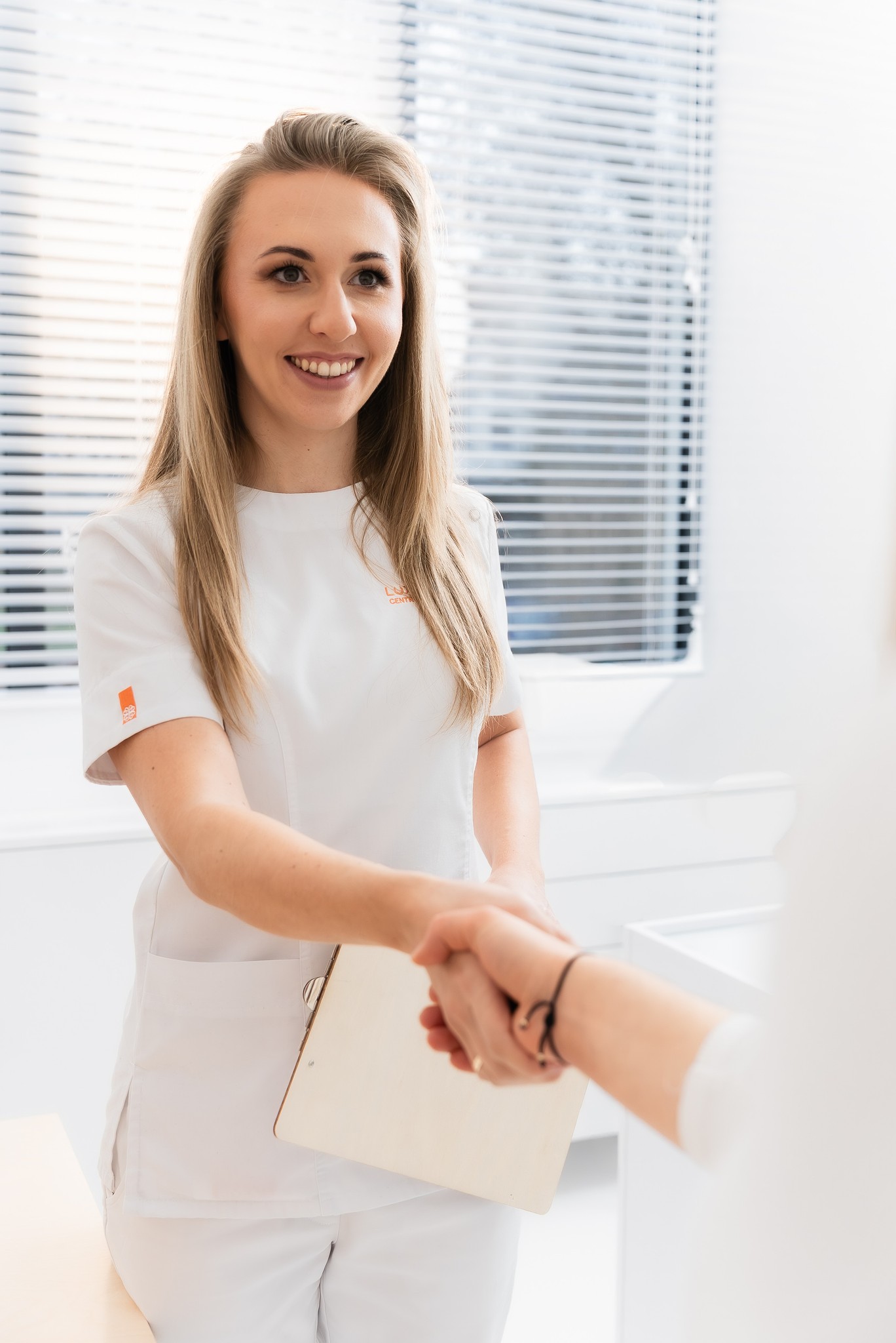 Dentystka z pacjentką na fotelu stomatologicznym, pacjentka ogląda zęby w lusterku.