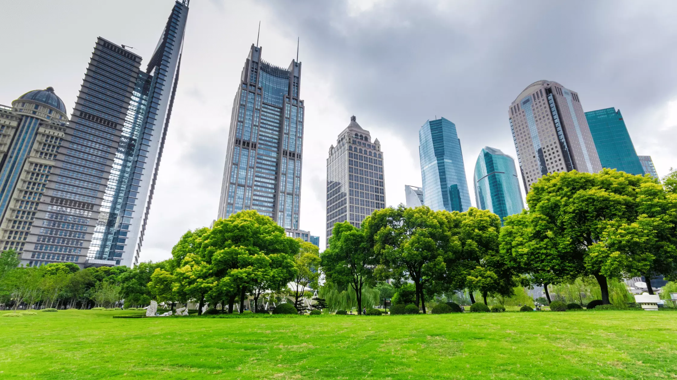 A man stands while two people sit at a table in an office setting, smiling and engaged in conversation. The mood is friendly and collaborative.