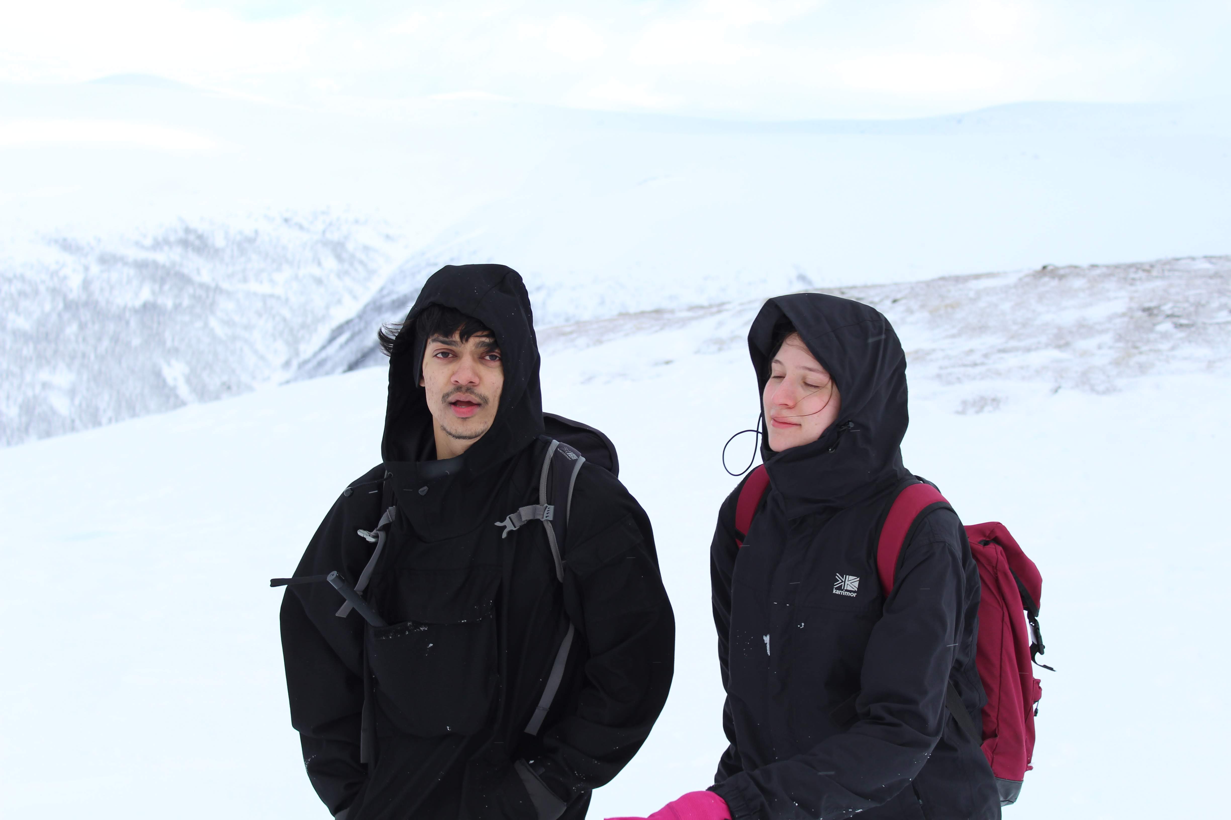 A serene outdoor wedding setup with white chairs arranged on green grass under a canopy of trees.