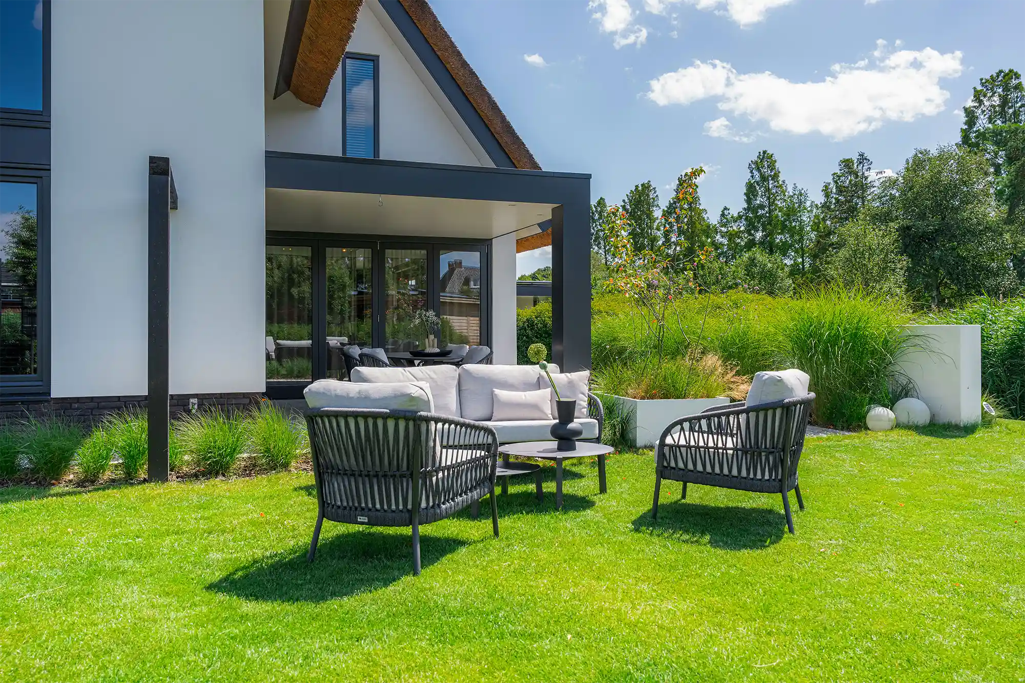 A modern outdoor living space with stylish seating and lush greenery.