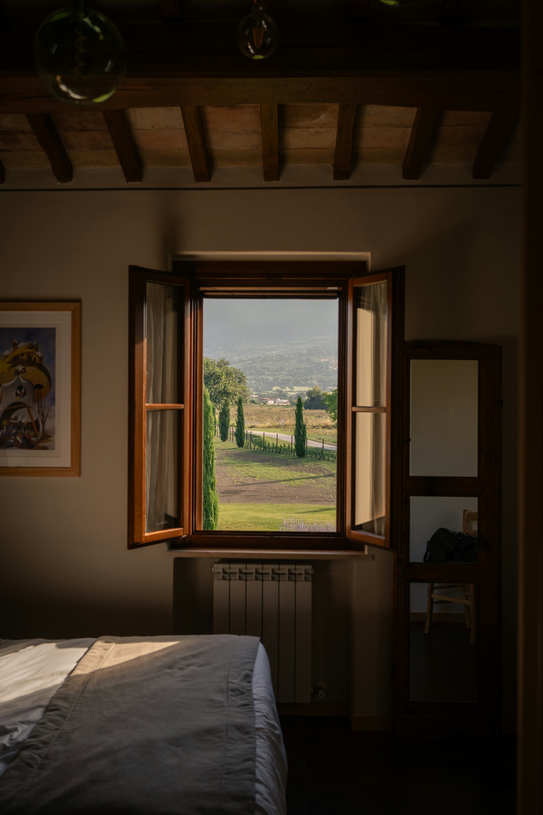 Open wooden shutters framing cypress trees and the valley