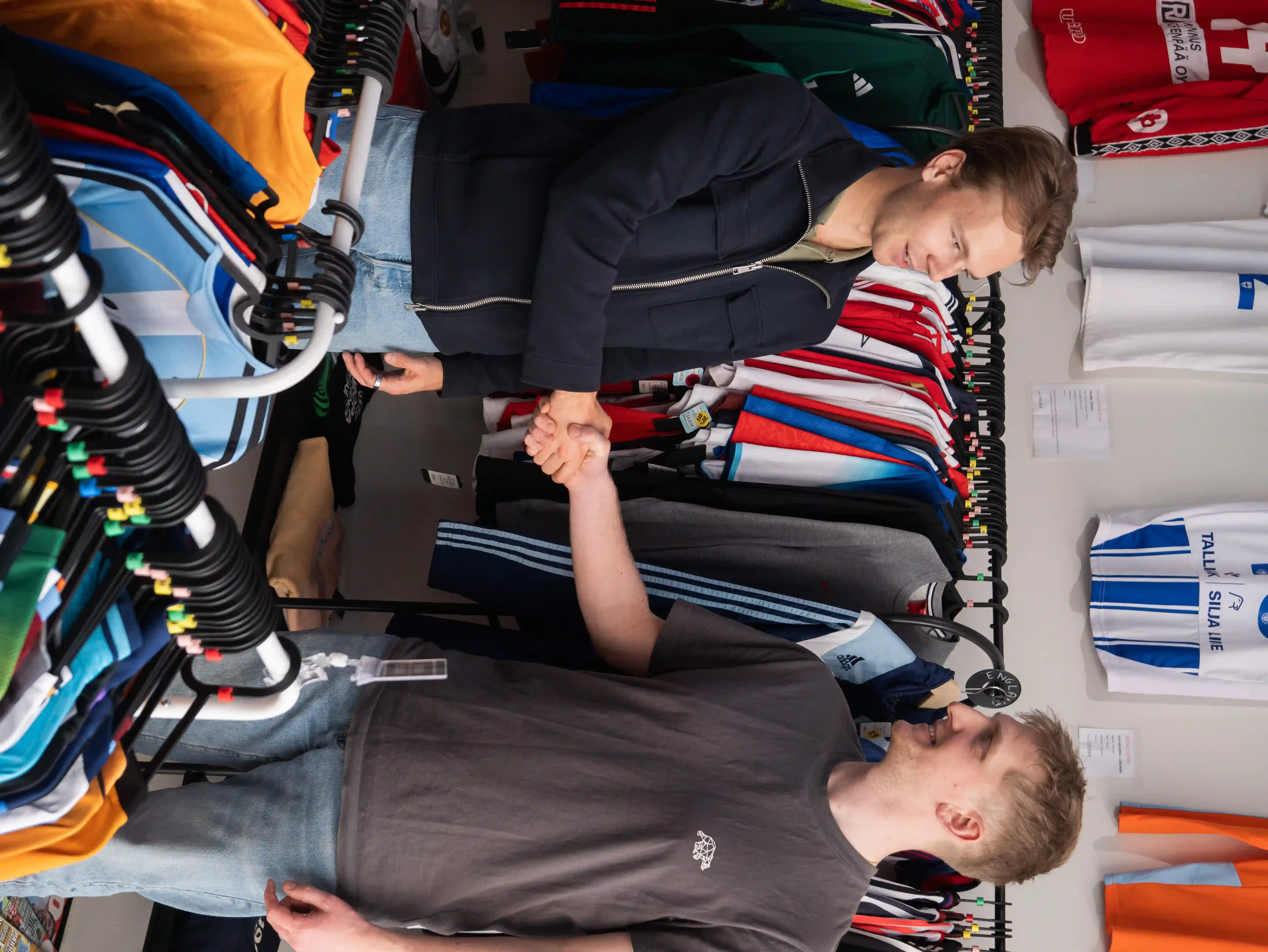 two men facing each other while shaking hands and smiling