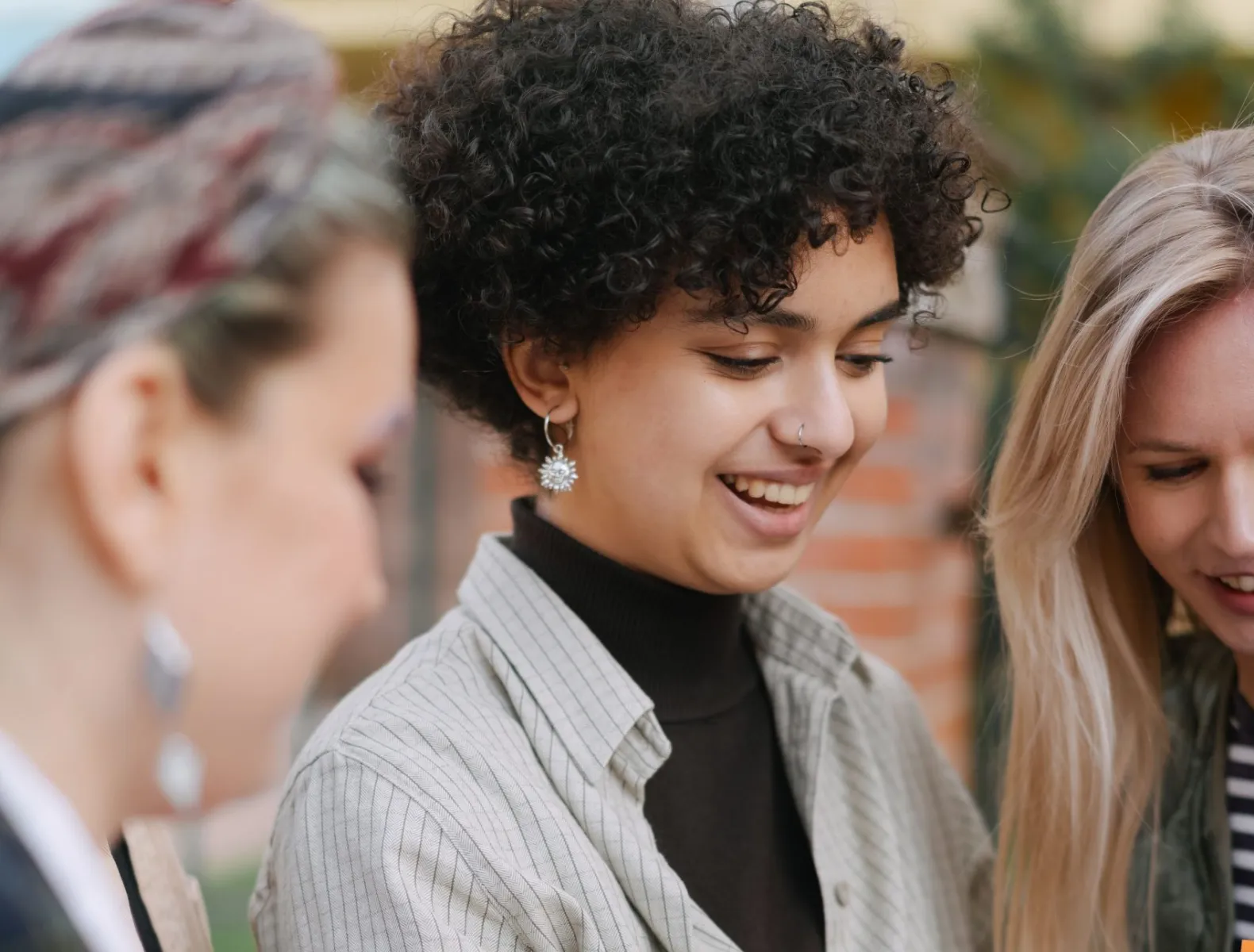 A group of three mid-20s women laughing together. 