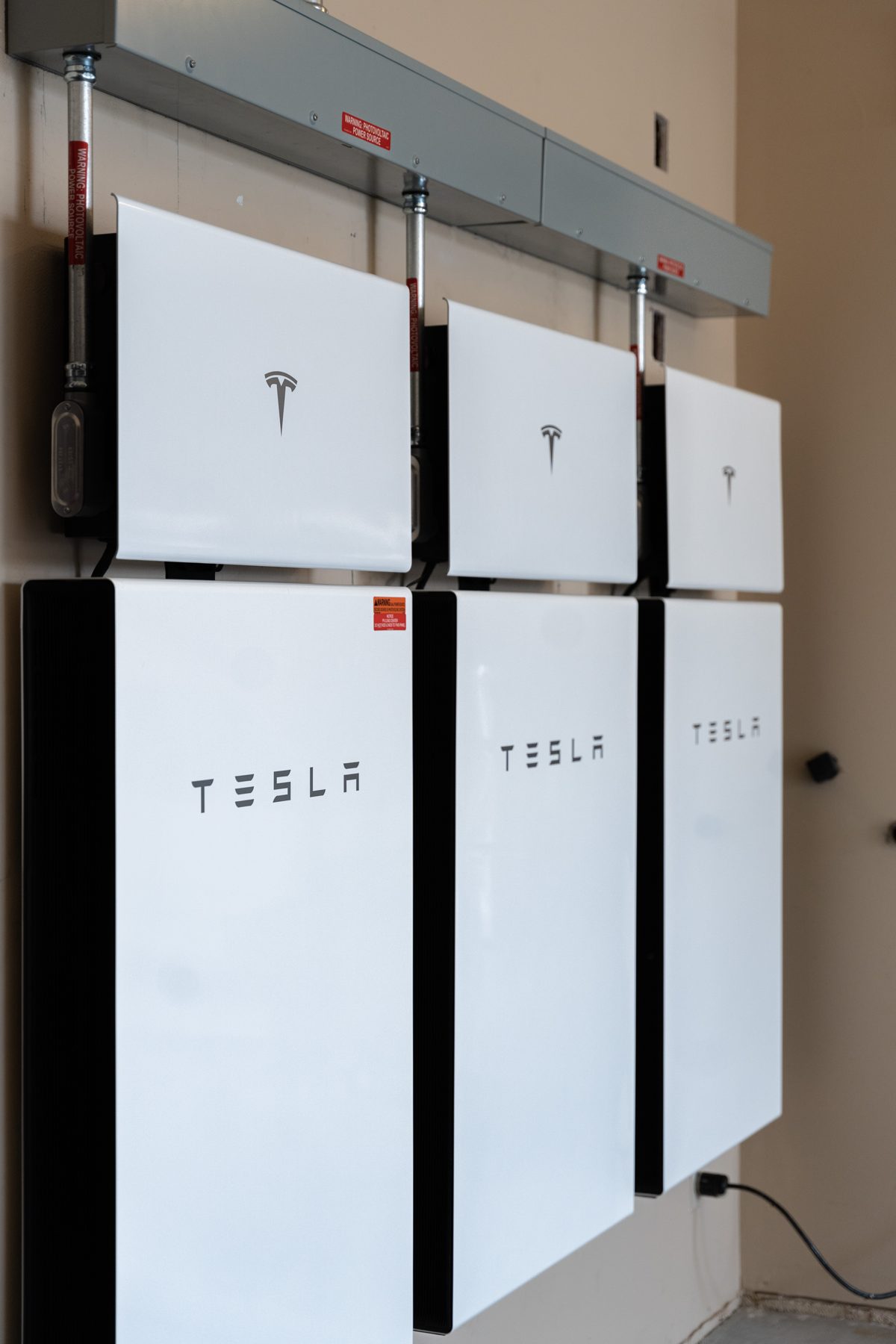 Tesla Powerwall batteries installed on a garage wall by Option One Solar