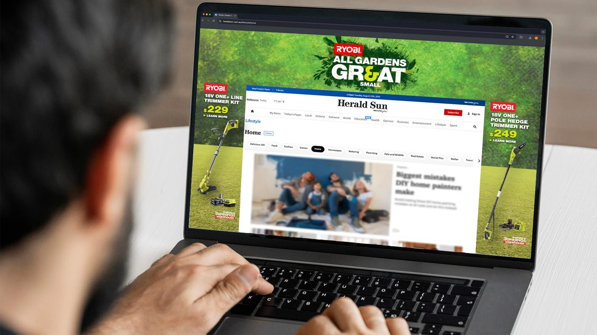 Laptop showing a Herald Sun homepage takeover with Ryobi 'All Gardens Great & Small' and 18V trimmer offers