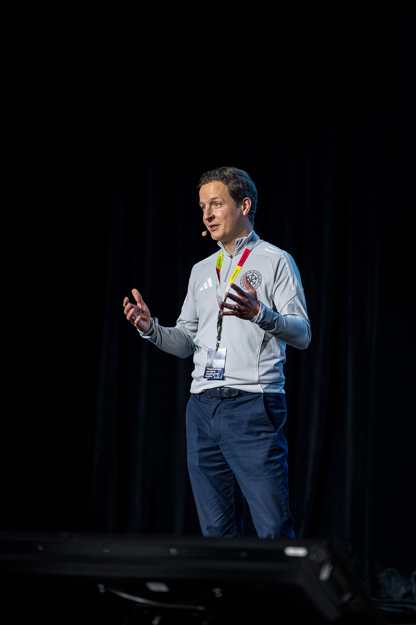 Keynote speaker presenting on stage during the CWS sales kickoff conference, captured against a dark backdrop with professional stage lighting.
