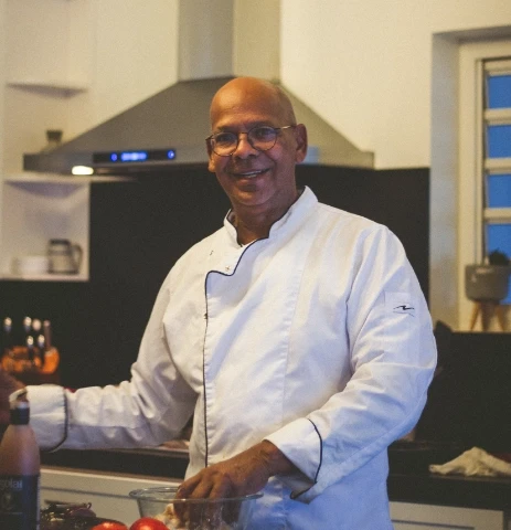 Chef Ronny preparing a dish, looking at camera smiling.