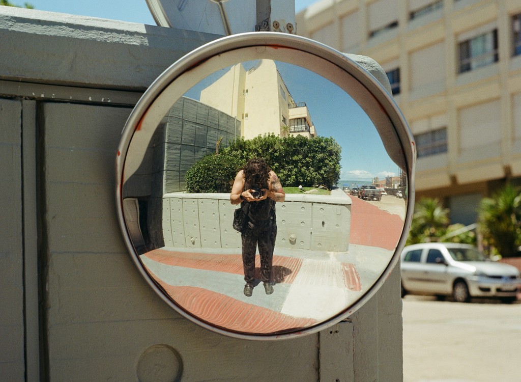 A person takes a selfie in a convex mirror.