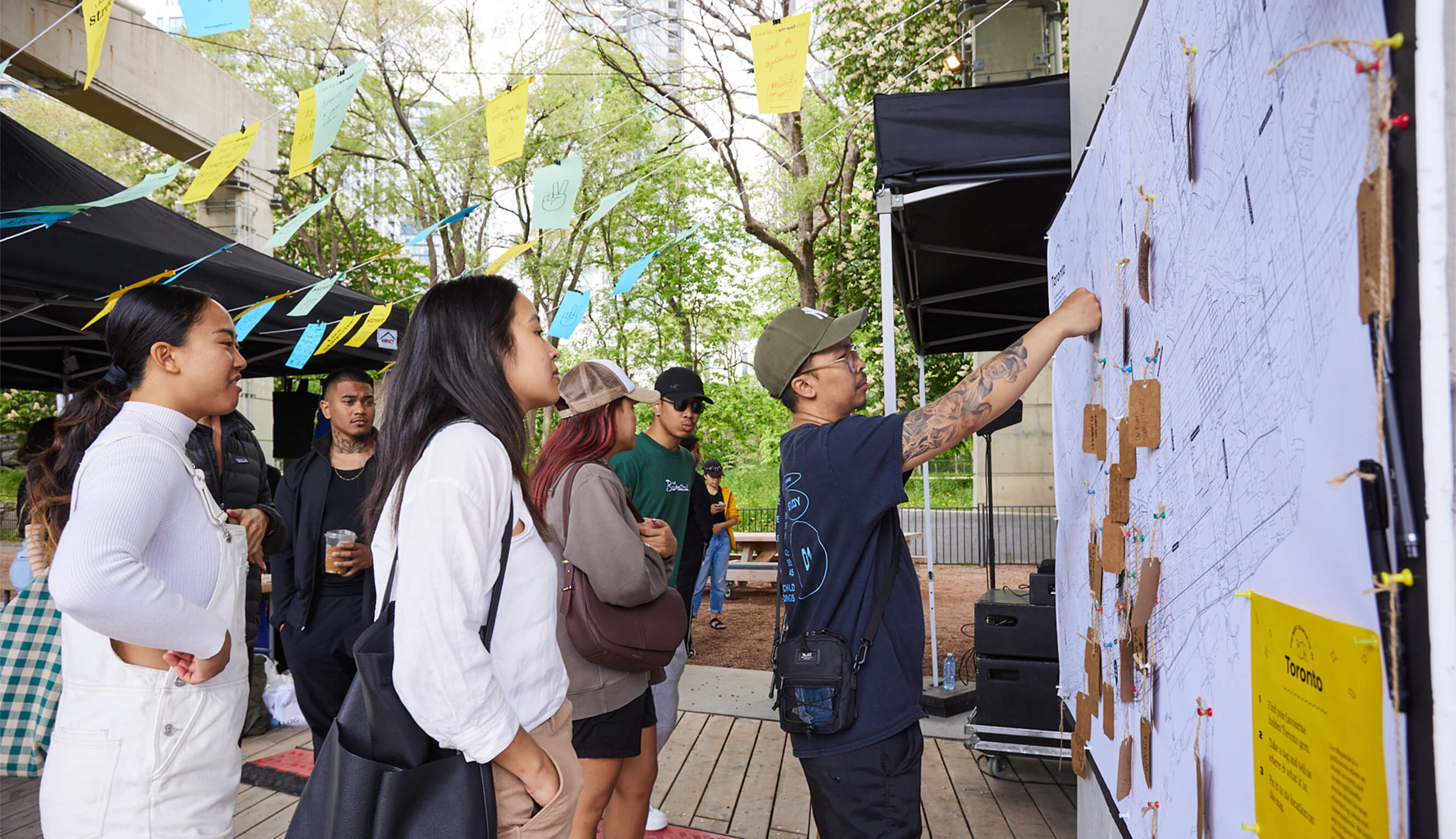 Group of young adults standing outdoors, looking at a Live Magazine activation.