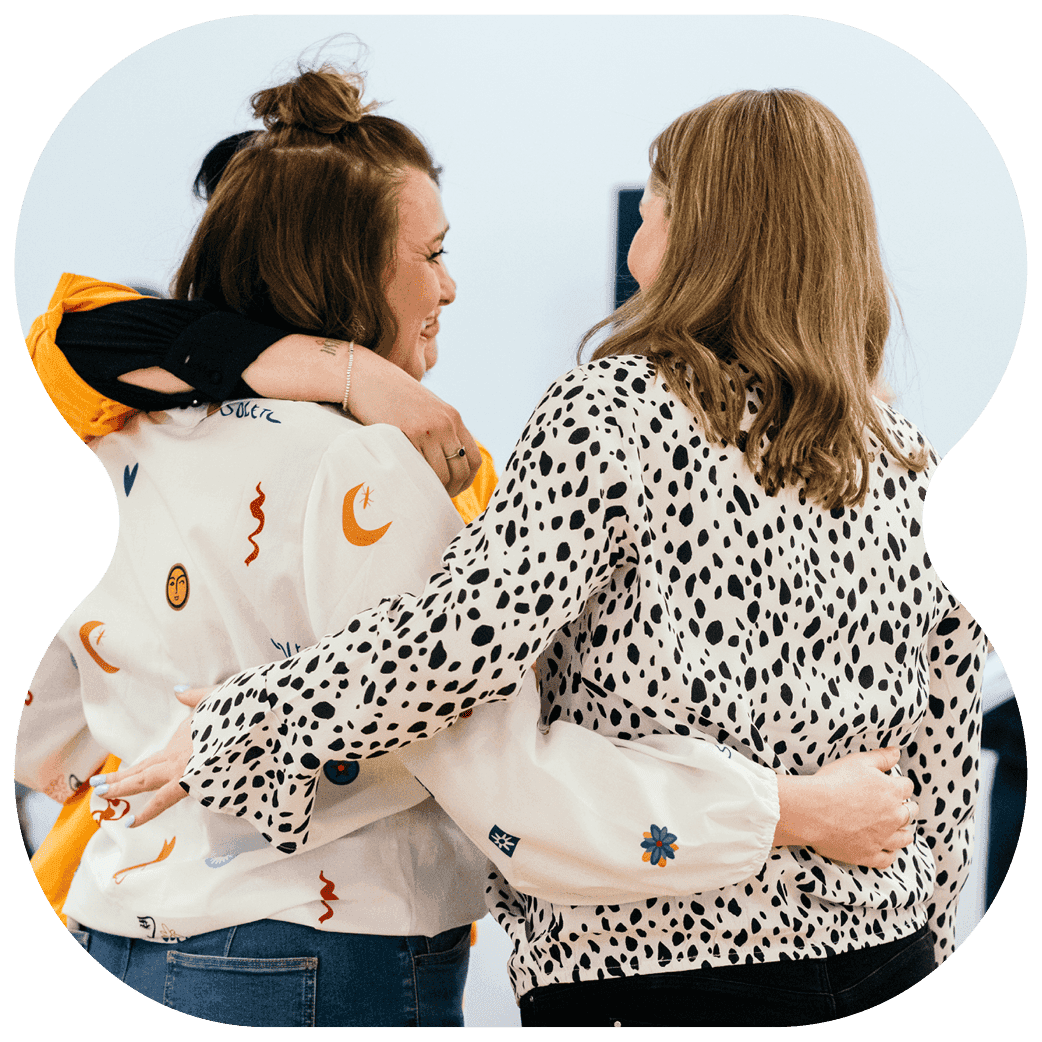 Three people standing with arms around each other in a supportive group embrace.