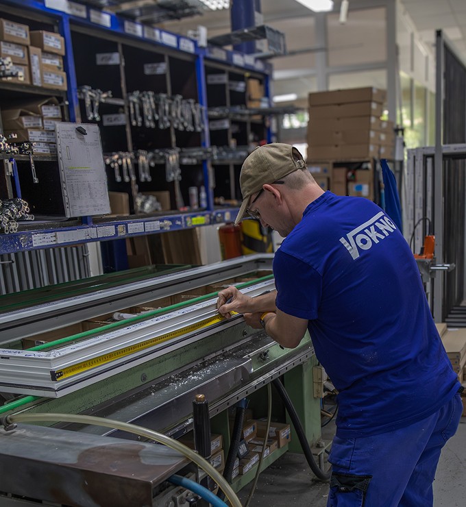 Pracovník v modrém oděvu obsluhující výrobní stroj