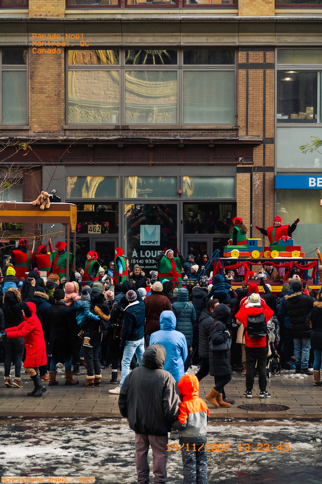 Parade de Noël à Montréal avec des lutins sur un char et une foule rassemblée.